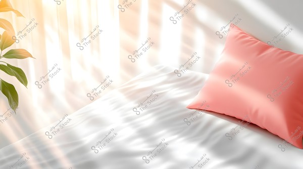 The image shows a bright room with a pink pillow placed on a bed covered with a white sheet. Sunlight streams through a window, creating shadows and light patterns on the bed. On the left side, a green plant adds a touch of nature to the room.