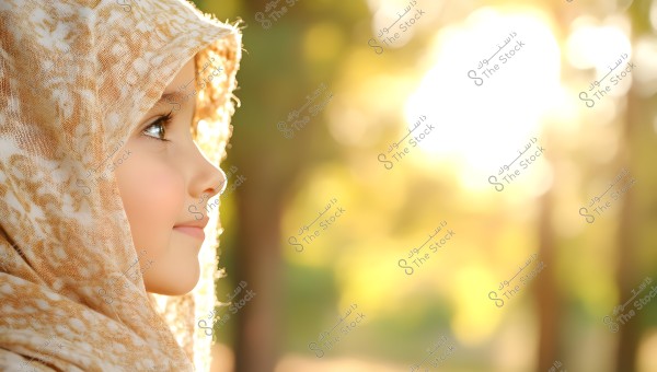 A close-up portrait of a young girl wearing a patterned light-colored headscarf, shown from the left side and looking towards the light. The background is blurred with soft sunlight flares, creating a warm and bright ambiance.