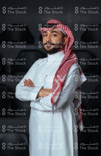 بورتريه رجل سعودي يرتدي الثوب ويقف أمام خلفية سوداء.