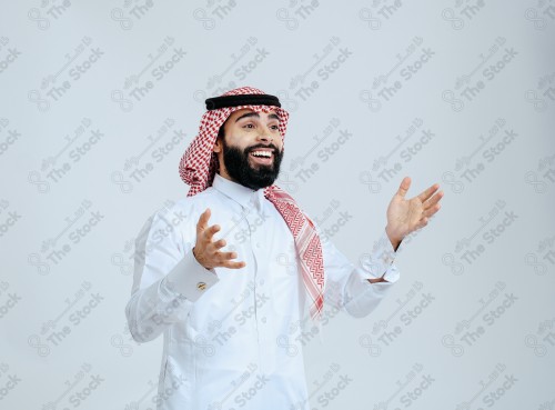 Portrait of a Saudi man in free uniform on a white background making gestures with his hands while smiling, souvenir photos, documenting a happy moment.