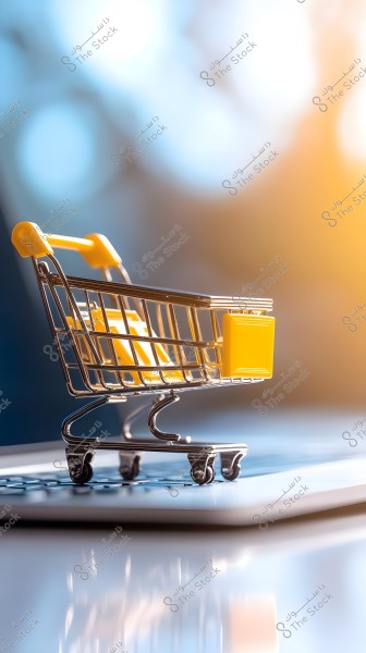 Image of a small shopping cart with a yellow handle placed on a tablet. The background is blurred with blue and orange hues, suggesting e-commerce or digital shopping.