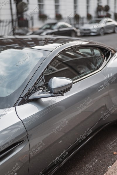 Image of part of a shiny silver car parked on a busy street.