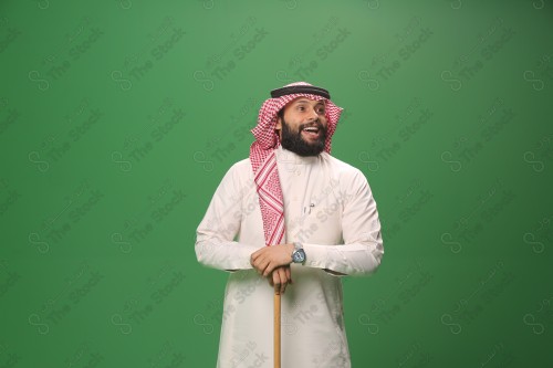 بورتريه رجل سعودي يرتدي الزي السعودي التقليدي يتكئ على العصا أثناء أداء رقصة المزمار الحجازية