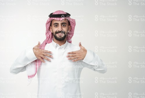 رجل سعودي يرتدي الزي السعودي الرسمي يشير بيده بحرف من حروف لغة الإشارة