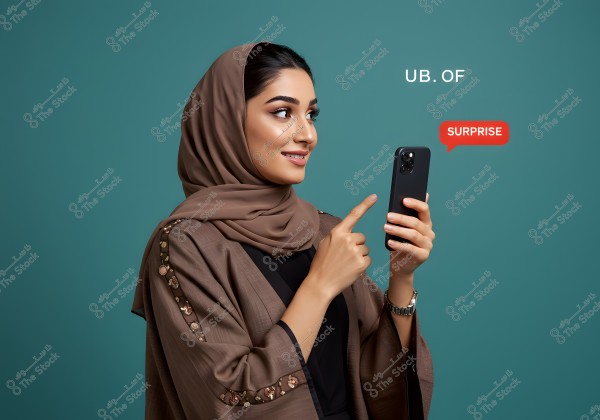 A photo of a woman wearing a brown hijab and an abaya with embroidered sleeves, looking at her phone and smiling while pointing at the screen. The background is blue, with text on the right showing \"SURPRISE\" in a red speech bubble.