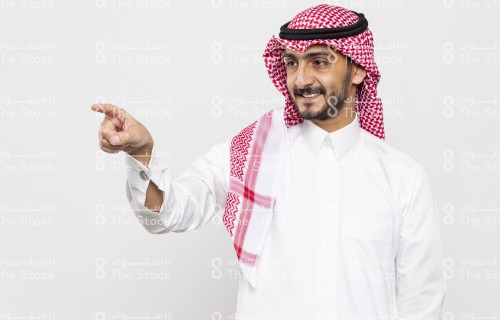 شاب سعودي يرتدي الزي السعودي التقليدي يشير بيده للأمام