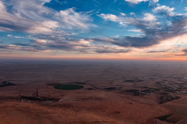 لقطة جمالية للكثبان الرملية الصحراوية بالسعودية وتظهر مزرعة في وسط الصحراء ، الرمال الذهبية في صحراء السعودية ، اثناء غروب الشمس .