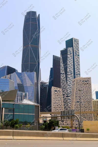 ** A view of a collection of modern skyscrapers featuring varied geometric designs and distinctive architecture. The buildings have glass facades and intricate patterns, reflecting a contemporary architectural style in the city. In the foreground, there is a highway with a few cars.\r\n\r\n**
