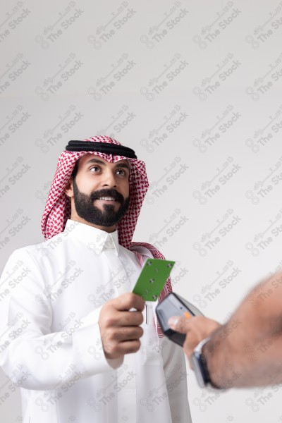 Portrait of a Saudi man holding a card and making automatic payments on a white background