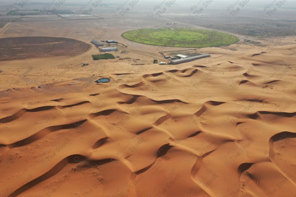 لقطة جمالية للكثبان الرملية الصحراوية بالسعودية وتظهر مزرعة في وسط الصحراء ، الرمال الذهبية في صحراء السعودية ، مناطق صحراوية .