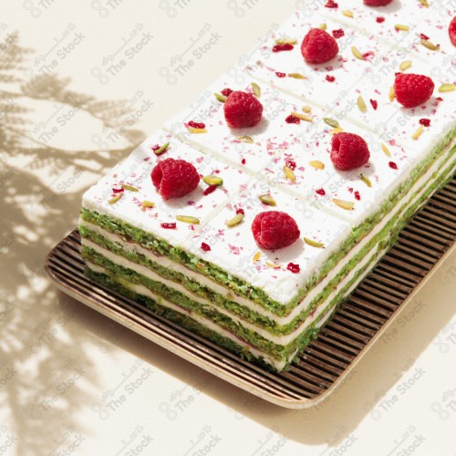 Close-up of raspberry slices with pistachios and topped with a red berry