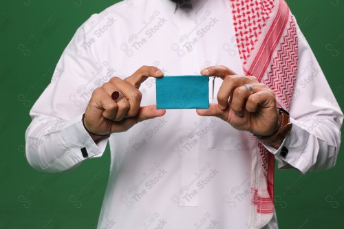 رجل سعودي على خلفية خضراء يحمل ببطاقة الصرافة مستعد للتسوق