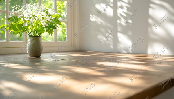 A bouquet of small white flowers in a ceramic vase placed on a wooden table near a glass window. Sunlight streams through the window, casting shadows on the table and walls, creating a serene and peaceful atmosphere in the room.
