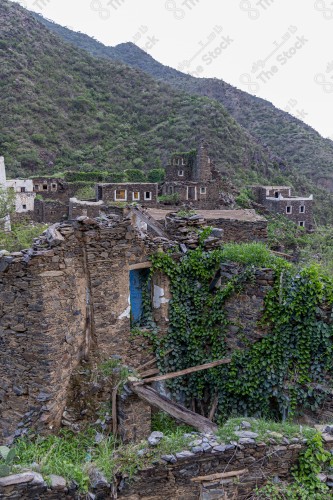 An ancient building built of stones in the middle of a group of windows surrounded by white paint while the sky looks cloudy during sunset, Rijal Almaa Heritage Village in the Asir region