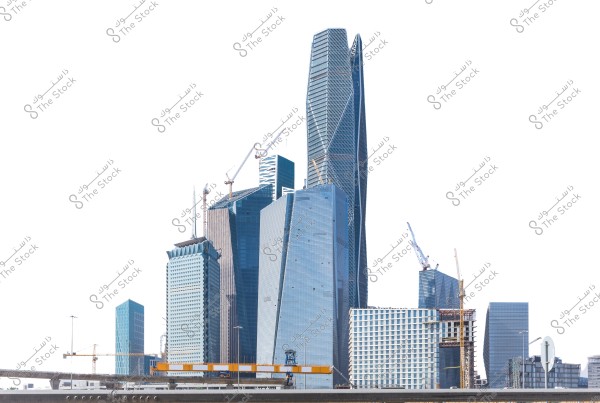 منظر لأفق مدينة حديثة يظهر مجموعة من ناطحات السحاب العالية بتصاميم معمارية معاصرة في مراحل بناء مختلفة. تبرز الرافعات في السماء فوق المباني, مما يعكس التطور والنمو العمراني. يظهر في الأسفل جزء من طريق سريع.