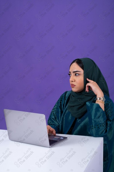 Portrait of a young Saudi woman wearing an abaya and hijab, holding a pen and thinking, against a purple background