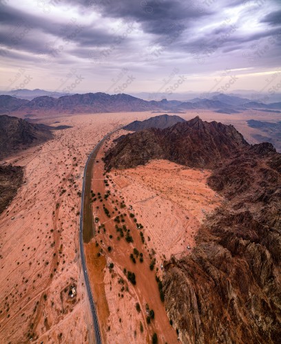 An overhead shot of a series of rocky mountains in Wadi Al-Bayda / Wadi Al-Jin, showing the sky cloudy during the day.