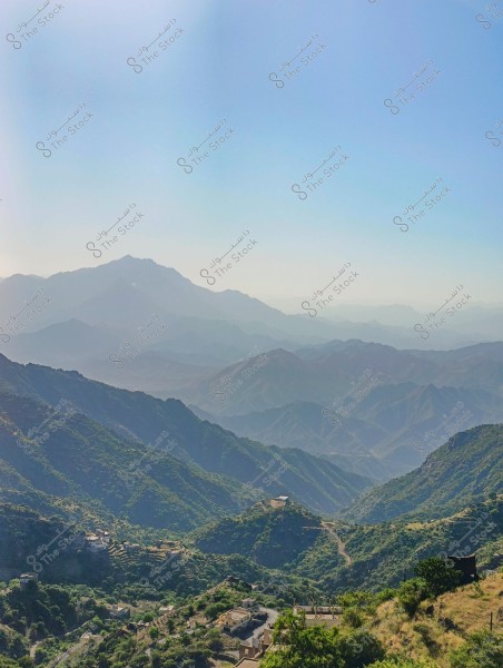 A scenic view of Al-Soudah Mountain in Saudi Arabia, showcasing a series of overlapping mountains lush with greenery and dense vegetation. The background features mountain peaks under a clear blue sky. A few scattered houses can be seen on the slopes, embraced by the beauty and charm of nature.