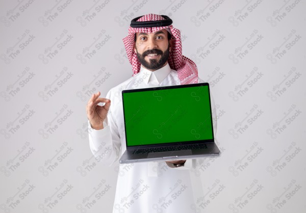 Portrait of a Saudi man holding a laptop, pointing at the laptop and making different expressions - green screen