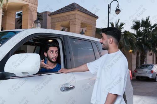 shot of two young Saudis chatting and having fun on the road, their features showing joy and happiness.