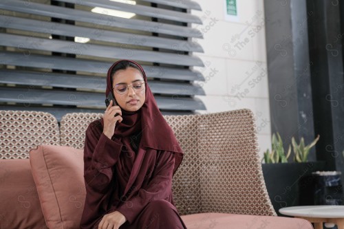 A Saudi woman wearing an abaya holds a mobile phone and displays its screen