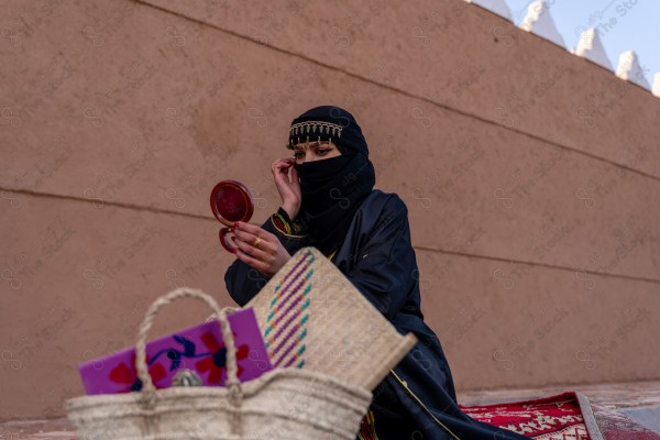 A shot of a Saudi woman whose eyes are reflected from the mirror wearing the traditional Saudi dress that represents the folklore, the day of foundation, the Saudi culture.