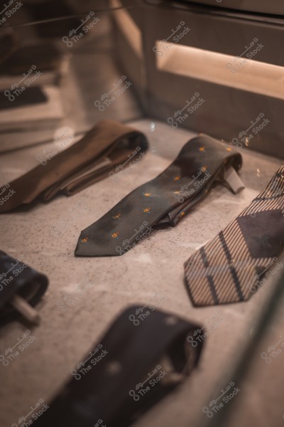 A collection of ties with different colors and patterns displayed on a glass display table in a store.