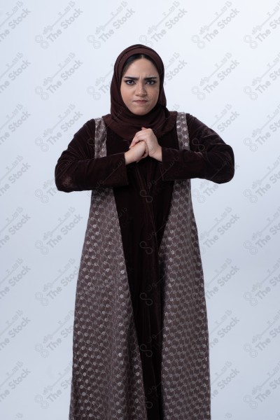 A young Saudi woman wearing an abaya and hijab, looking angry