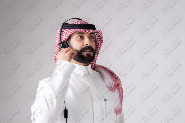 بورتريه رجل سعودي يلبس سماعة الرأس ويقوم بالتواصل عبر السماعة - خدمة العملاء ، مكالمة هاتفية