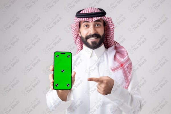 Portrait of a Saudi man holding a phone, pointing at the phone and making different expressions - green screen