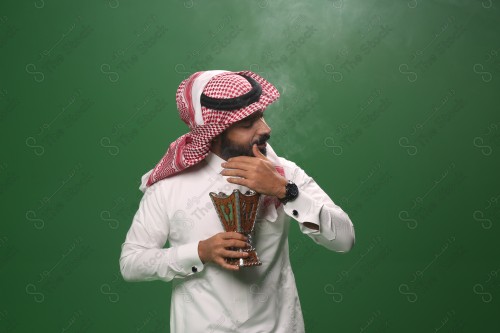 بورتريه رجل سعودي يرتدي الزي السعودي التقليدي يحمل المبخرة ويتطيب بالبخور