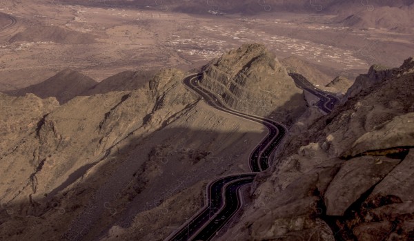 لقطة لسلسلة من الجبال الصخرية الشاهقة والطرق المعبدة الممتدة في جبال الهدا بالطائف ، وتظهر السماء ملبدة بالغيوم وقت الغروب، مرتفعات الجبال ، جبال الطائف ،  سلسلة جبلية.