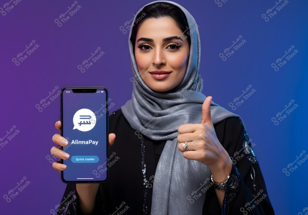 A portrait of an Arab woman wearing a black embellished abaya and a shimmery silver hijab, holding a smartphone displaying the \"AlimaPay\" app with a button labeled \"Quick transfer\". The woman is giving a thumbs-up gesture, indicating approval or satisfaction, against a blue and purple colored background.