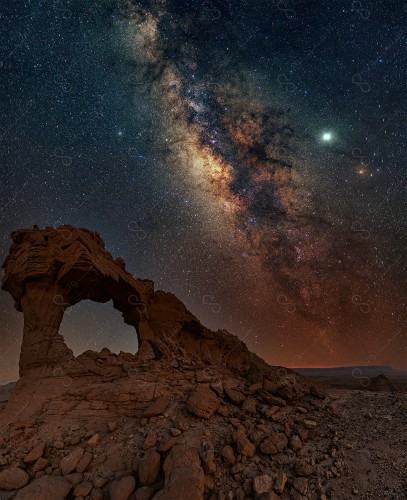 A night shot in one of the Saudi deserts, whose sky is decorated with stars and meteors, the Milky Way, a group of rocky mountains in the desert