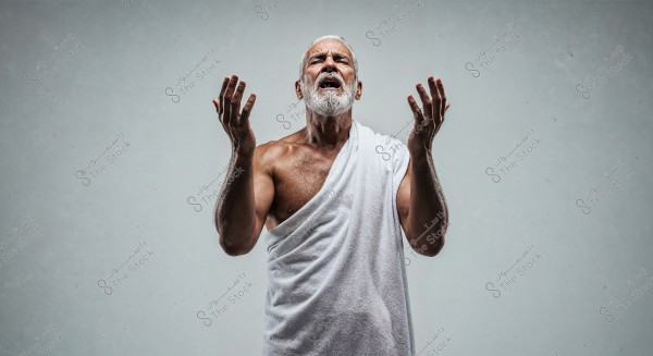 A portrait of an elderly man with a white beard, wearing a white wrap covering half of his body. The man is in a stance with his hands raised, appearing to be praying or meditating. The background is white, highlighting the details of his attire and expression.