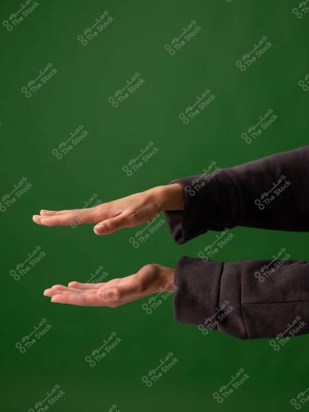 يدان ترتديان ملابس داكنة أمام خلفية خضراء, في وضع أفقي.