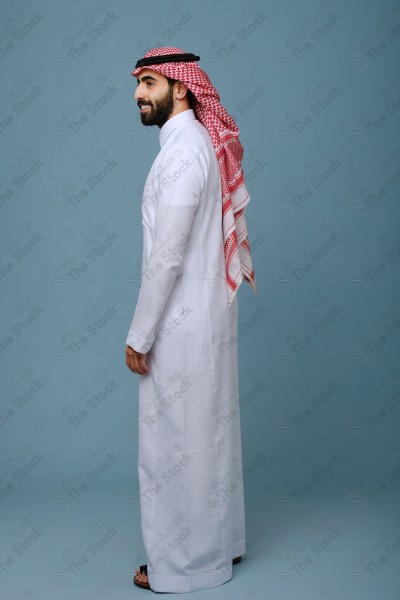 Portrait of a Saudi young man wearing the Saudi dress, and happiness and joy appearing on his features, against a heavenly background