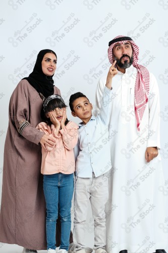 Portrait of a Saudi family looking towards a place, two children standing next to their parents pointing towards a goal, signs of happiness, a happy family atmosphere, the concept of a happy family, spending enjoyable family times