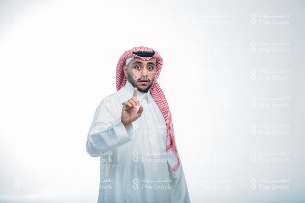 بورتريه رجل يرتدي الثوب ويقف أمام خلفية بيضاء،  يتفاعل بإشارات تعبيرية بيديه، تعابير وجه تدل على الانفعال والحماس في نقاش