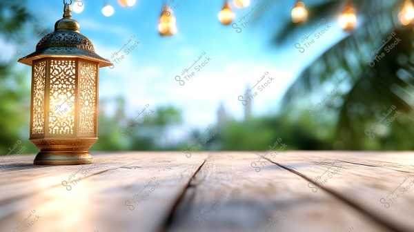An image of a candle inside a traditional Arabic lantern placed on a wooden surface. The lantern is adorned with intricate geometric patterns and emits a warm glow. In the background, small colorful lights are hanging, and palm tree leaves are visible, suggesting a festive atmosphere, possibly in a garden.