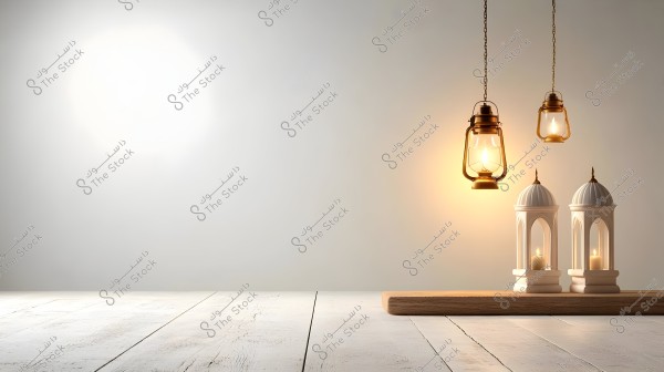 An image showcasing a serene indoor setting with two hanging lanterns made of gold-colored metal, glowing warmly. Below the lanterns, there are two candles placed in decorative holders resembling Islamic minarets, set on a wooden base. The background features a light-colored wall and a wooden floor.