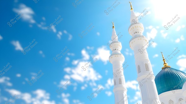 The image shows a white minaret with golden details next to a blue dome, set against a clear blue sky adorned with scattered white clouds. The architectural design is traditionally Islamic.