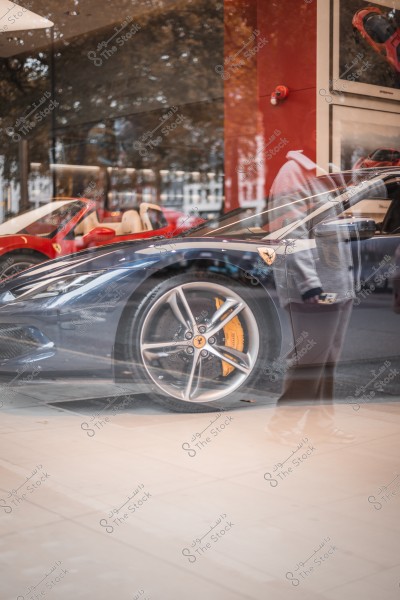 انعكاس شخص في نافذة عرض لسيارة فيراري, معروضة في معرض سيارات.