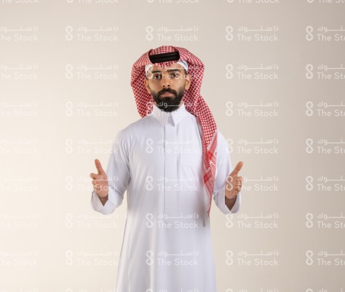 شاب سعودي يرتدي الزي السعودي التقليدي يمد كفيه للأمام