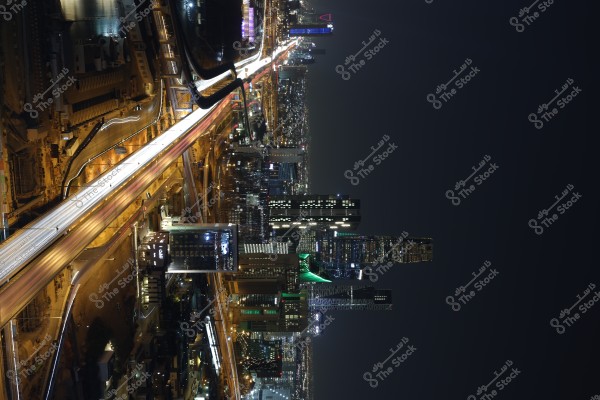 Night view of Riyadh city in Saudi Arabia showing the illuminated city skyline. High-rise buildings are lit up, with street lights tracing the curves of the roads, and the Kingdom Tower prominently visible in the background.