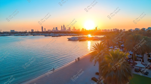 A sunset view over a city skyline filled with skyscrapers, likely Dubai, with tall buildings clearly visible. In the foreground, a sandy beach lined with palm trees and boats docked on the calm waters. The sky is filled with orange and golden hues, creating a warm impression.