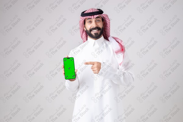 Portrait of a Saudi man holding a phone, pointing at the phone and making different expressions - green screen