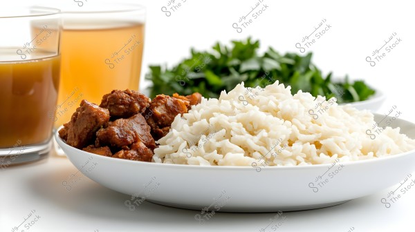 Image of a plate of white rice next to browned pieces of meat in a white dish. In the background, fresh green leaves, possibly parsley, and two glasses of light brown juice are visible on a white surface.