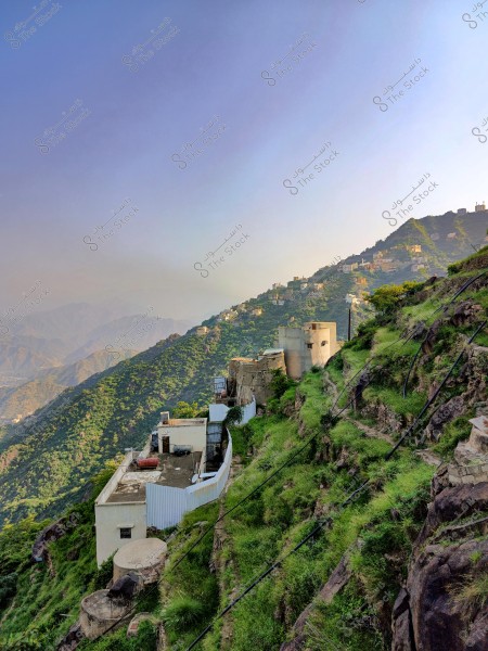 منظر طبيعي لجبل محافظة فيفاء بمنطقة جازان جنوب المملكة العربية السعودية أخضر مزدهر بالمباني البيضاء في منطقة جبلية. تظهر المنازل متدرجة على المنحدرات المغطاة بالعشب الأخضر, مع سماء صافية في الخلفية.