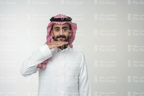 رجل سعودي يرتدي الزي السعودي الرسمي يشير بيده بحرف من حروف لغة الإشارة